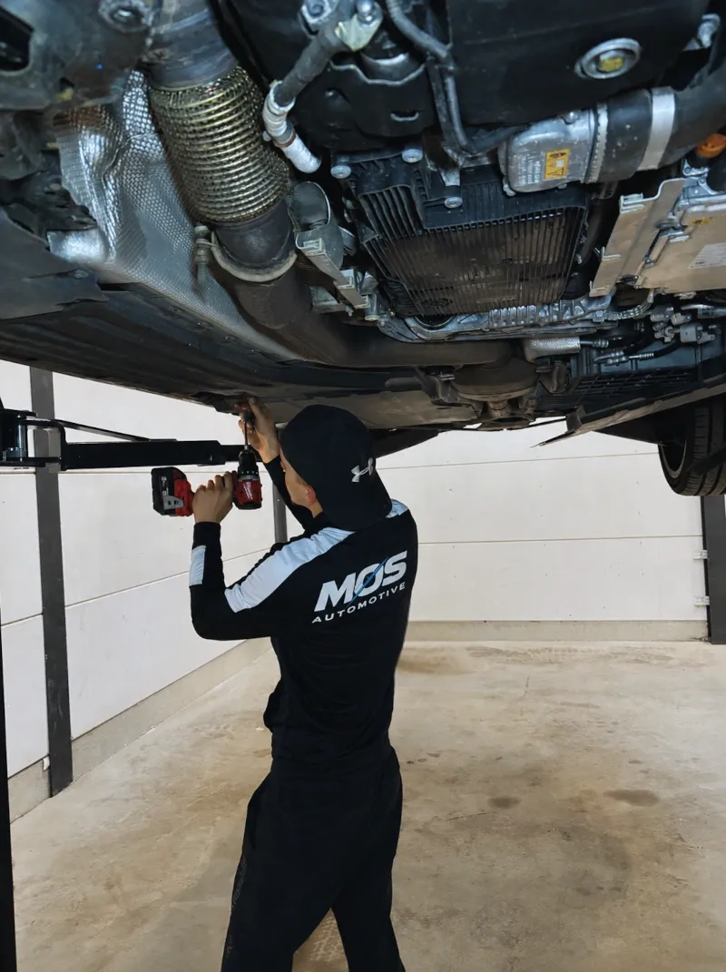 Monteur van Mos-Automotive aan het werk onder een wagen op de brug